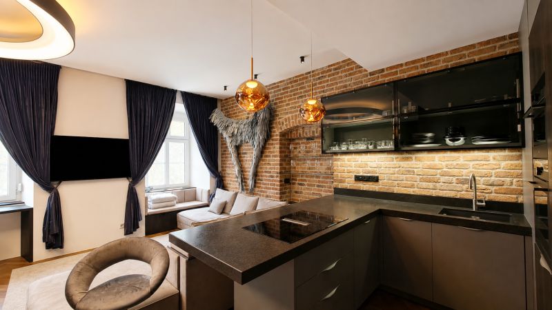 A kitchen in a 2-room apartment with a brick wall and dark-colored curtains.