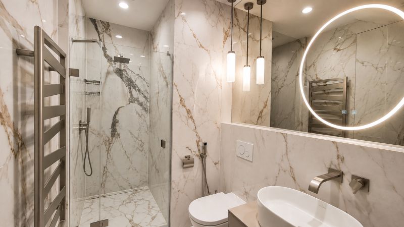 A bathroom with marble tiles in a 2-room apartment, featuring a large mirror and a shower corner.