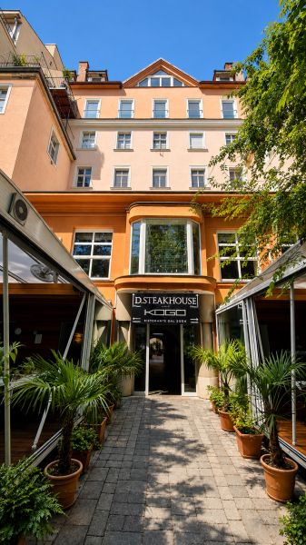 A restaurant on Hviezdoslav Square in Bratislava - Old Town, surrounded by greenery and palm trees.