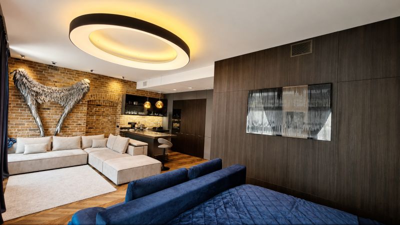 A room decorated with brick, a sofa, and modern lighting, complemented by a floor with a wooden decor.
