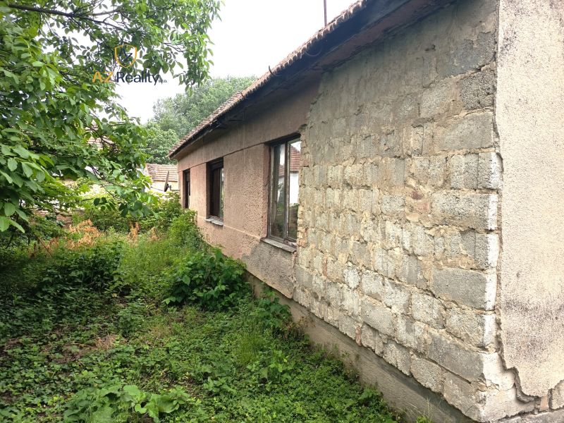An older family house in Nové Zámky with an unmaintained garden and a wooden roof structure.