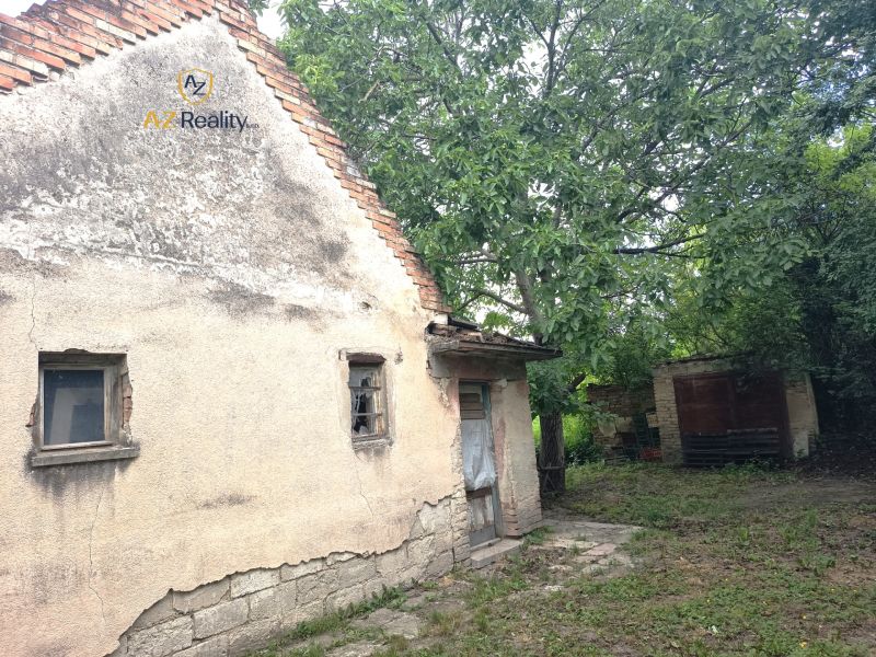 An older family house in Nové Zámky surrounded by greenery with damaged walls.