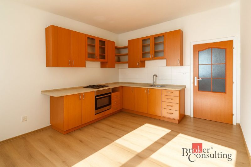 A kitchen in a 2-room apartment with wooden cabinets and a floor with a wood decor.
