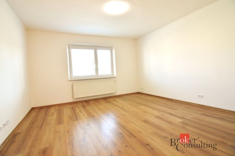 A spacious room with a wooden decor floor in a 2-room apartment.
