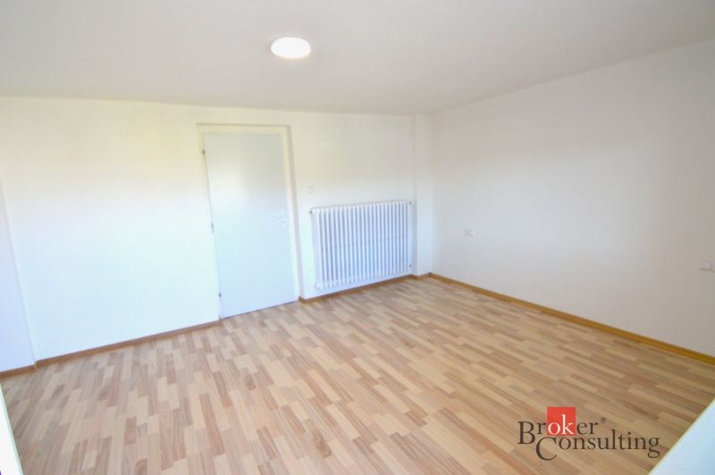 A room with white walls and a wooden decor floor in a 2-room apartment.
