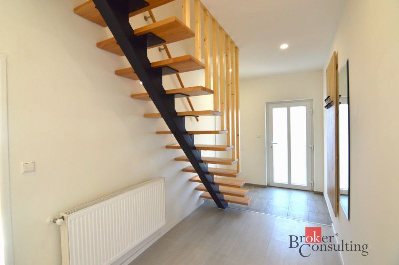A staircase with a wooden decor floor, entrance, and radiator in a 2-room apartment.
