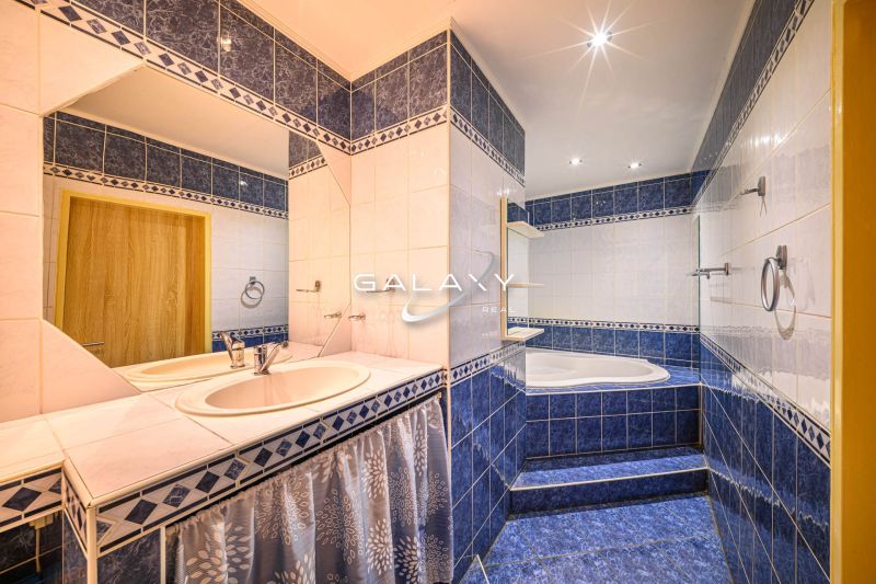 A bathroom with blue tiles and two sinks in a two-room apartment.