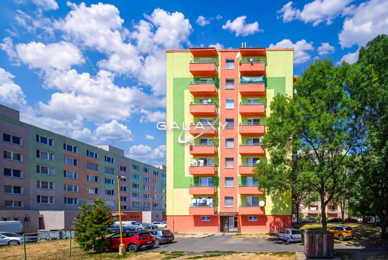 Colorful apartment buildings on Sládkovičova Street in Fiľakovo with parking and greenery.