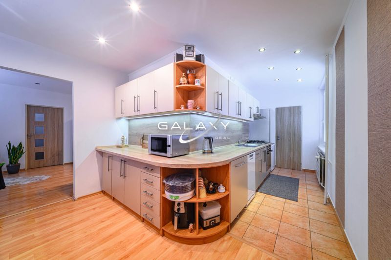 A kitchen in a 2-room apartment with a wooden decor floor and modern appliances.
