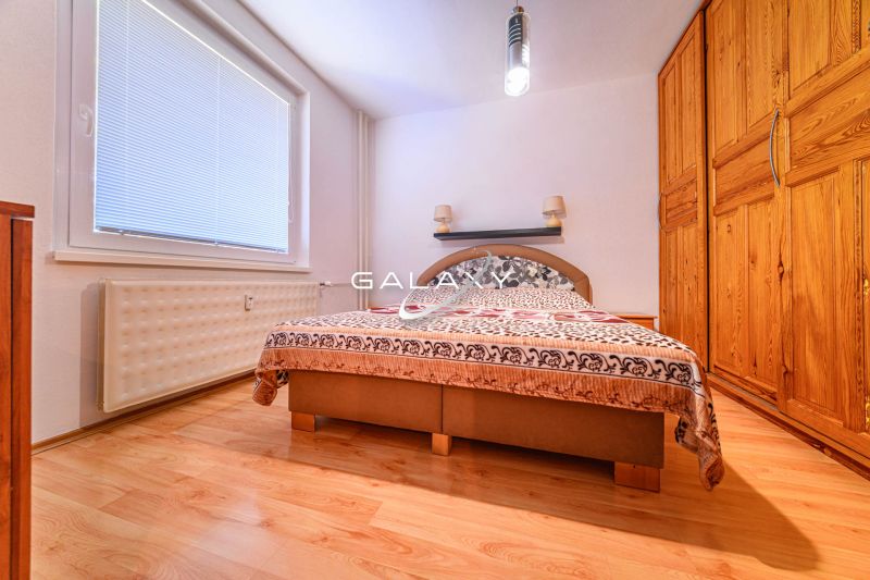 A bedroom with a wardrobe and a wooden decor floor in a 2-room apartment.