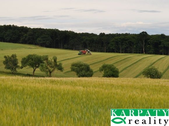 Agricultural and forest land in Bukovec with trees, a combine harvester, and a grain field.