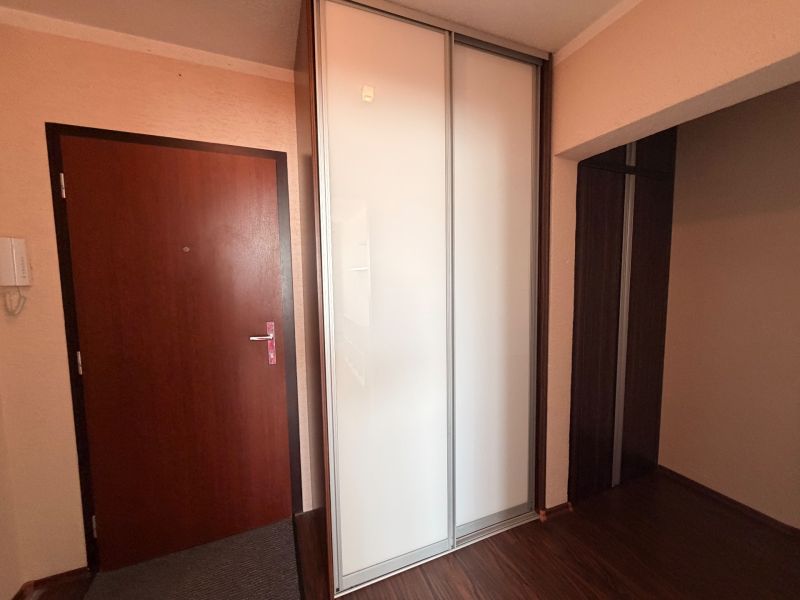 The hallway in a 3-room apartment with a white wardrobe and a wooden decor floor.