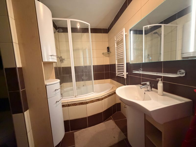 Bathroom in a 3-room apartment with a bathtub, shower, sink, and furniture.