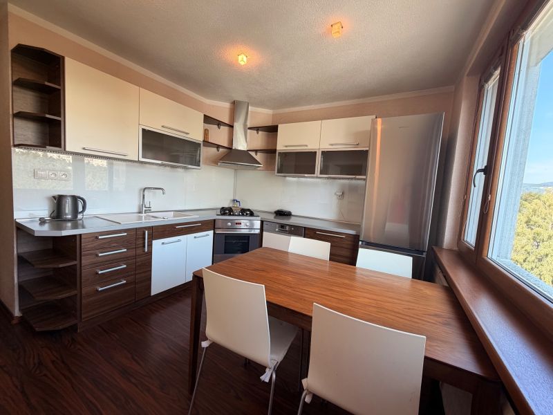 A kitchen with white cabinets, a wooden decor floor, and a dining table.