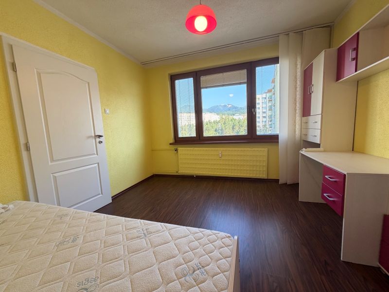 Yellow walls of the room with a wood-patterned floor in a 3-room apartment.