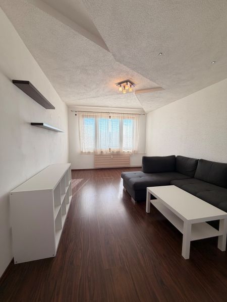 Living room in a 3-room apartment with a wooden decor floor and a corner sofa.