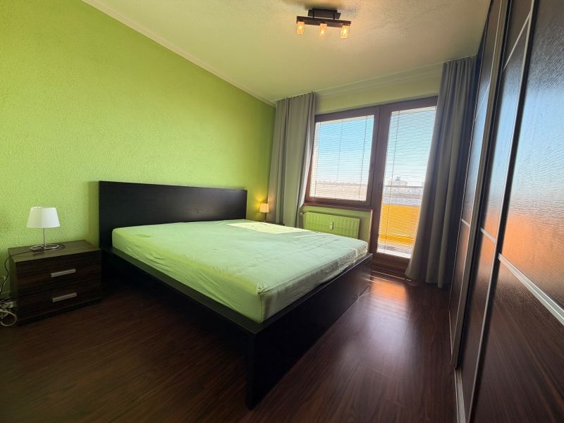 A bedroom in a 3-room apartment with a wood-decor floor and green walls.