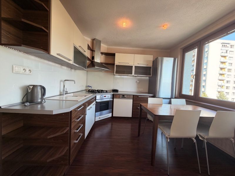A kitchen in a 3-room apartment with a wooden decor floor and a dining table.