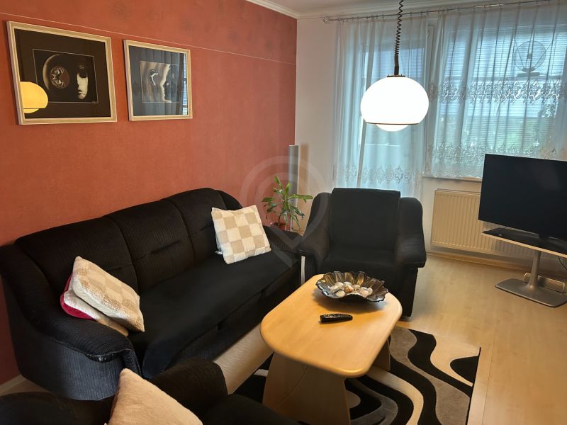 Living room in a three-room apartment with a sofa, table, and wall decorations.