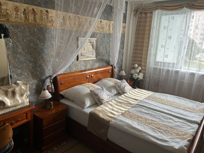 A bedroom with a double bed and oriental decorations in a three-room apartment.