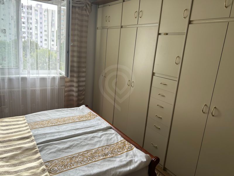 Bedroom in a 3-room apartment with built-in wardrobes and an open window to a green environment.
