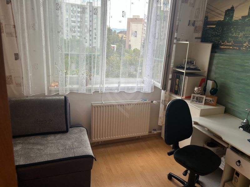 A work corner in a 3-room apartment with a wooden decor floor and a writing desk.