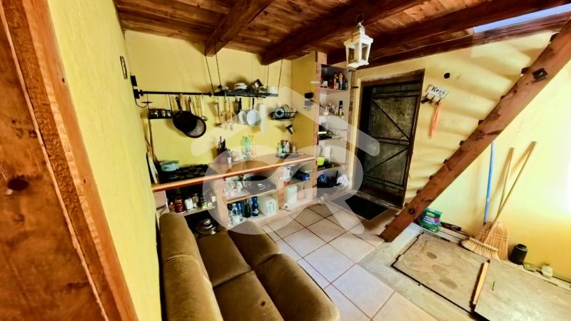 The interior of the cottage with a rustic kitchenette and wooden ceiling creates a cozy space.