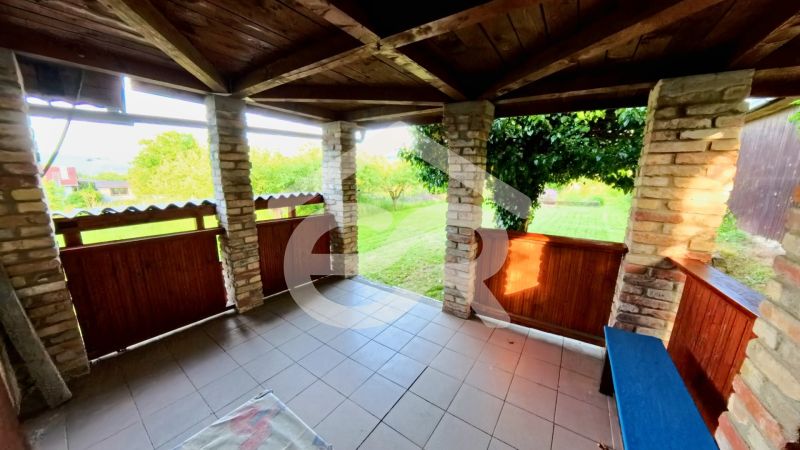 Stone pillars and wooden railing on the terrace of the cottage in Podhorany near the meadow.