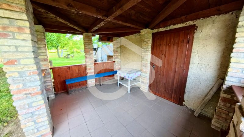 A wooden gazebo at the cottage in Podhorany with brick walls and garden furniture.
