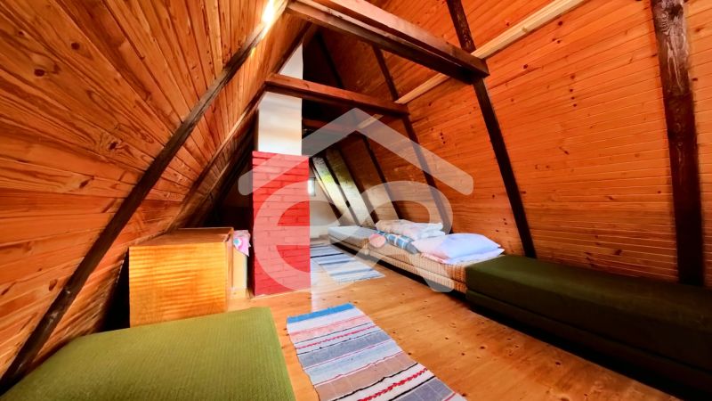 The attic of the cottage with a wooden decor floor and simple beds.