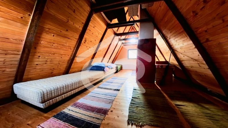 A wooden interior of a cabin with a bed and a carpet on the floor with a wooden decor.