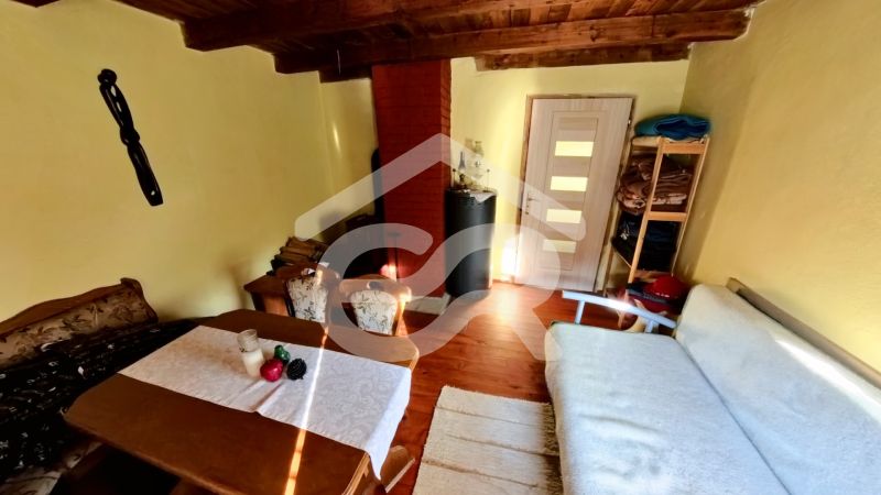 Living area in a cottage with a wooden decor floor, a sofa, and a table.