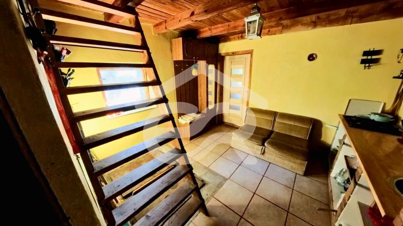 The interior of a cabin with wooden stairs, a couch, and tiled flooring.