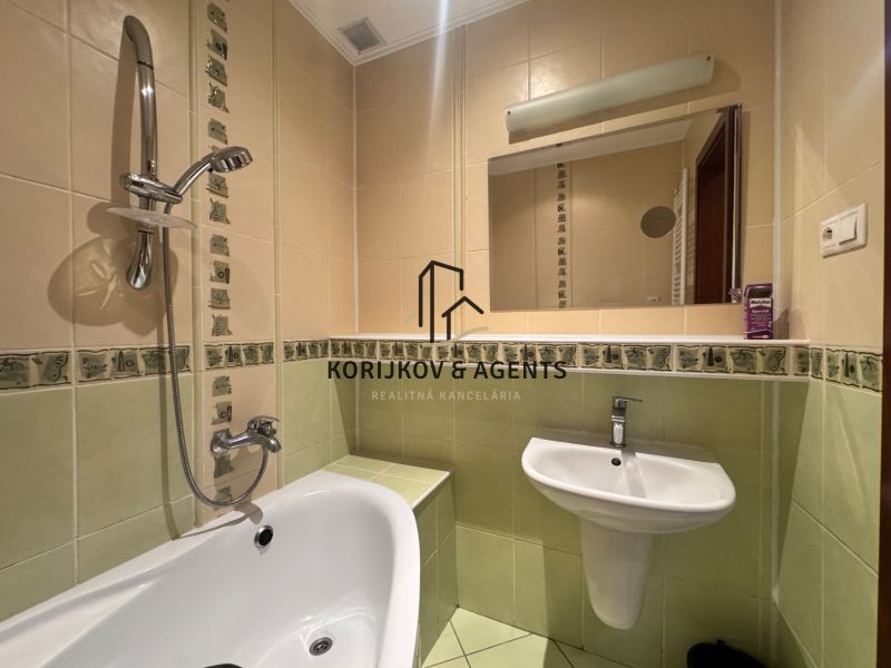 A bathroom in a 4-room apartment with a bathtub, sink, and mirror.