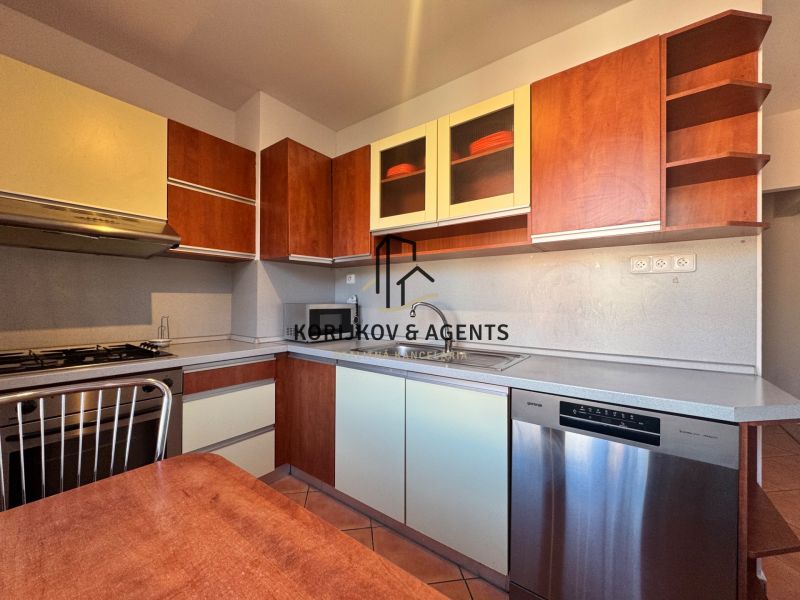 A kitchen in a 4-room apartment with a dishwasher and a kitchen unit with a wooden decor.