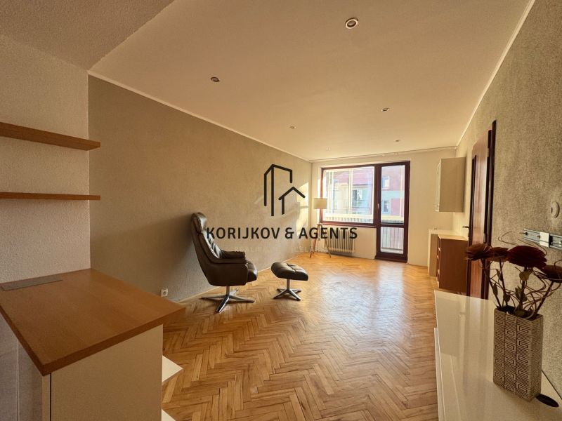 Living room in a four-room apartment with a wooden decor floor and a comfortable armchair.