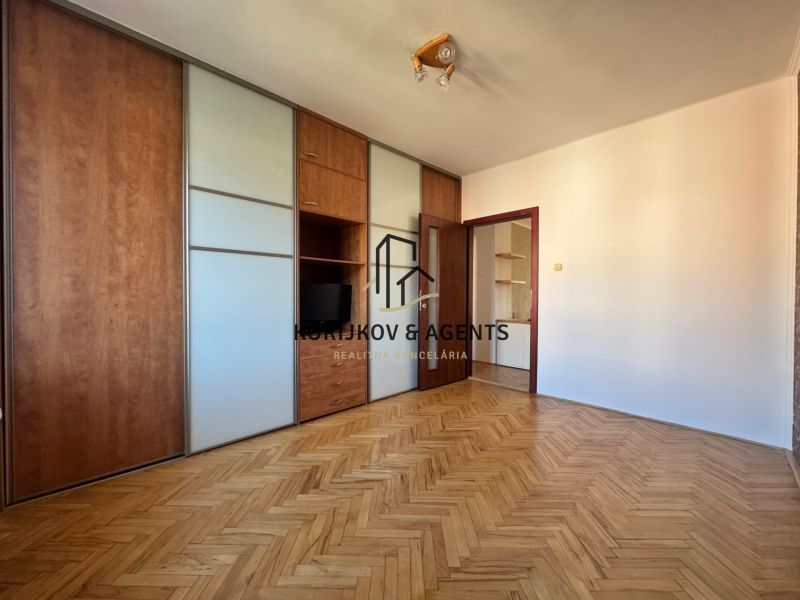 A room in a 4-room apartment with a wood-patterned floor and a built-in wardrobe.