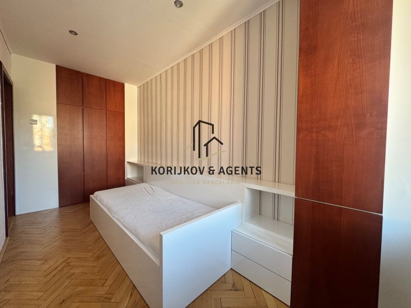 A bedroom in a 4-room apartment with a wood-patterned floor and built-in wardrobes.