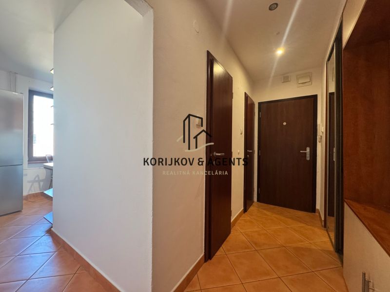 A hallway in a 4-room apartment with tiles and wooden doors.