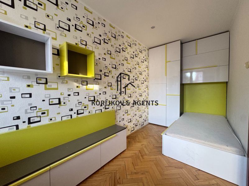 Children's room with graphic wallpaper, built-in wardrobes, and a floor with wood decor in a 4-room apartment.