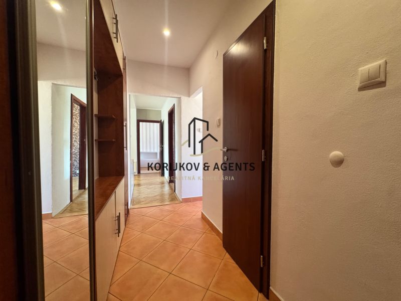 Hallway of a 4-room apartment with tiles, in the background a floor with a wooden decor.