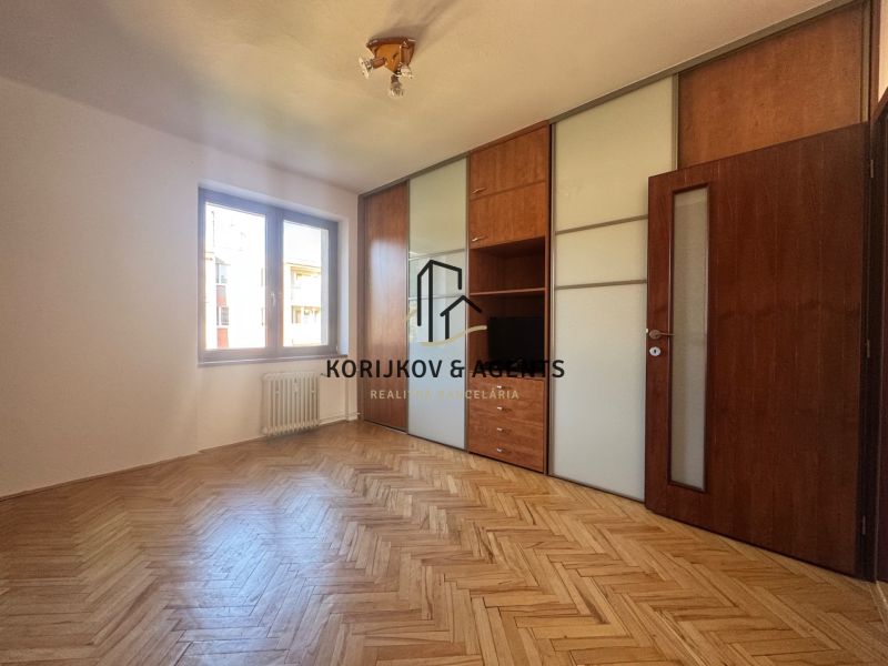 A room with a built-in wardrobe and a wooden decor floor in a 4-room apartment.