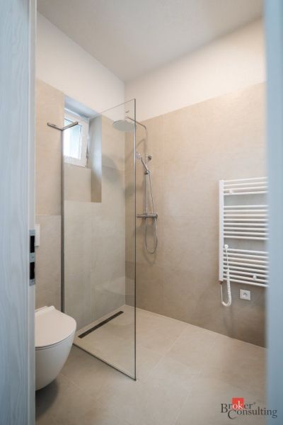 Bathroom in a 3-room apartment with an open shower and light tiles.