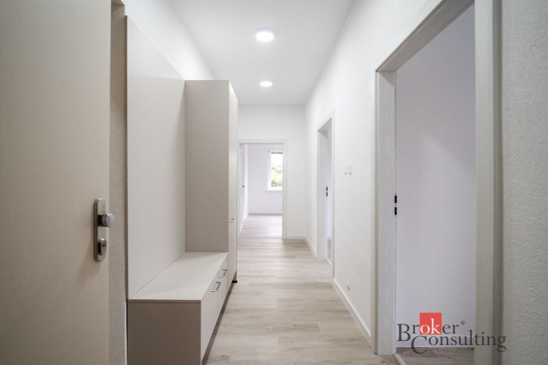 A bright hallway in a 3-room apartment with wood-patterned flooring and furniture.