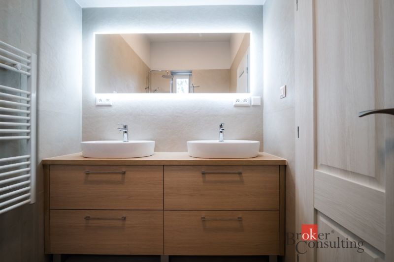 A bathroom with a cabinet with two sinks in a 3-room apartment, backlit mirror.