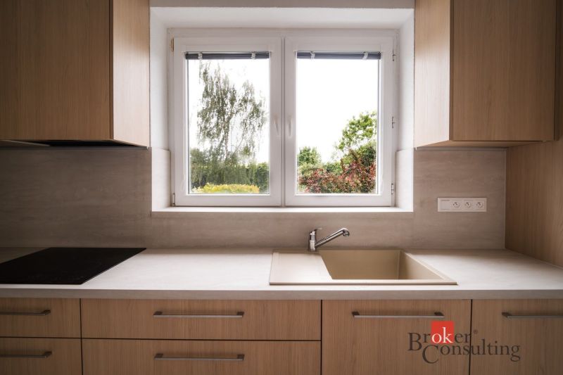 A kitchen in a 3-room apartment with a wooden decor floor and a view of the garden.