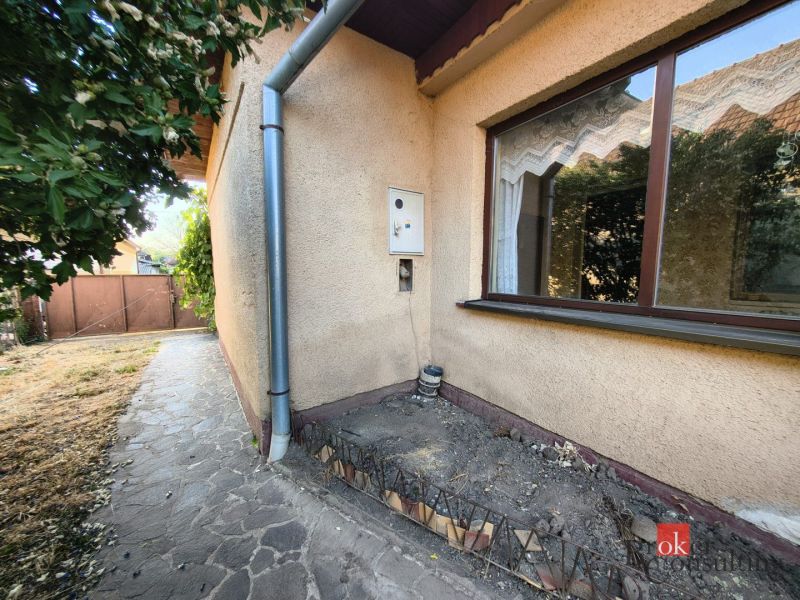 A family house in Ladice with a stone path along the wall and a garden.