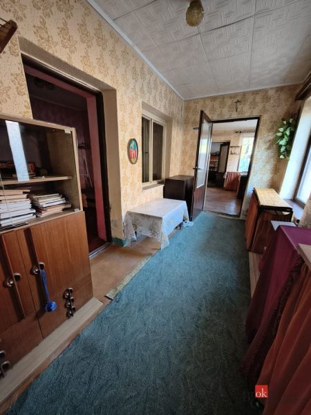 A hallway in a family house with a carpet, wooden furniture, and wallpapered walls.