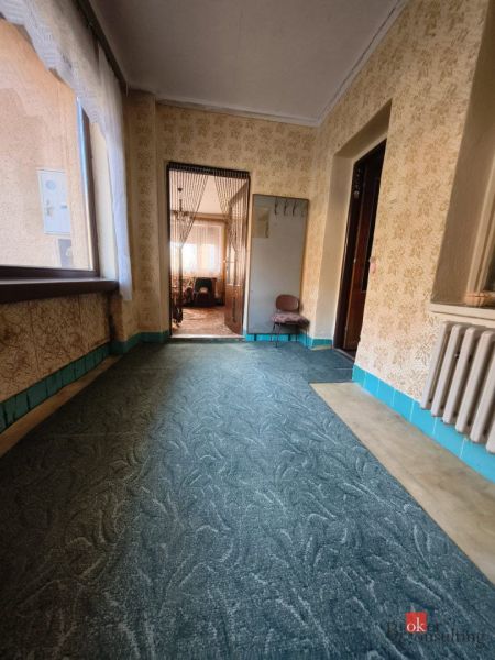 A hallway with carpet in a family house with a view of another room.