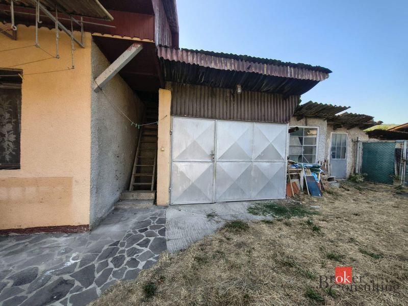 A family house in Ladice with a metal garage and a stone walkway.